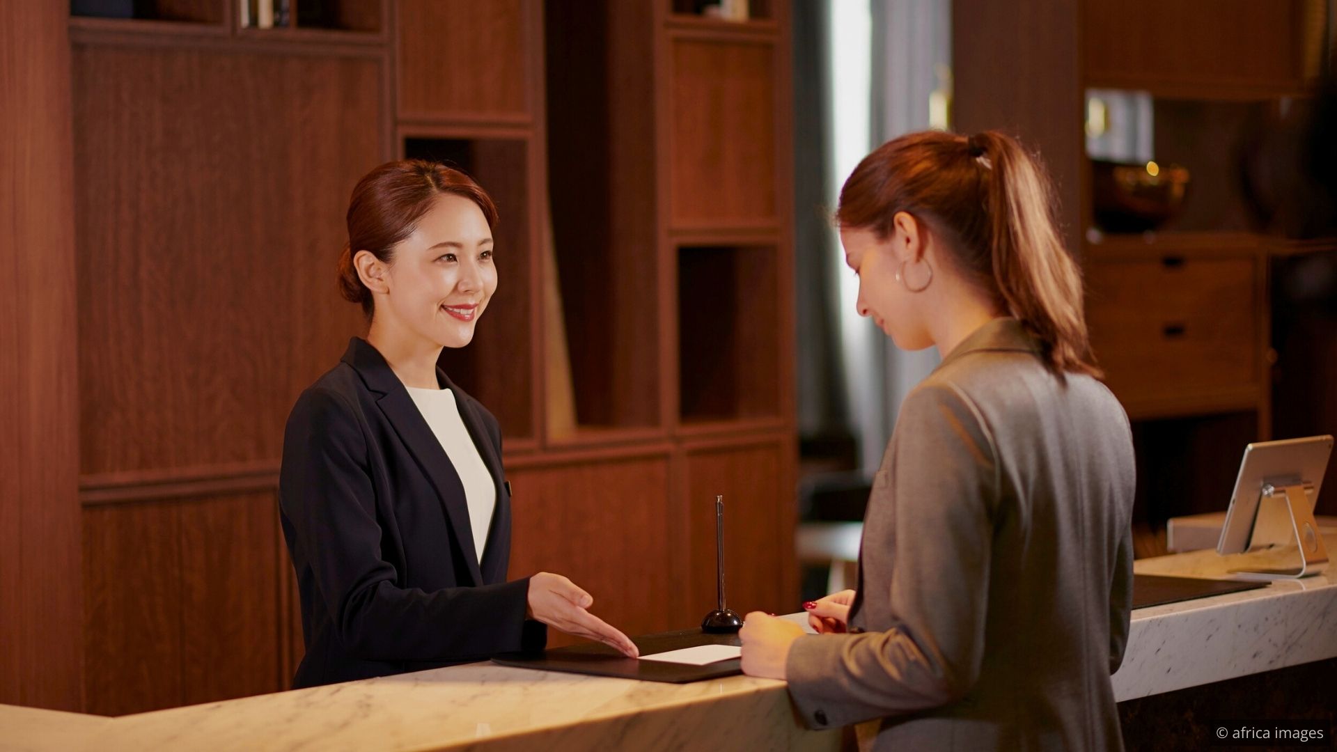A hospitality team gathered around a table during a pre-shift meeting with a manager leading the conversation