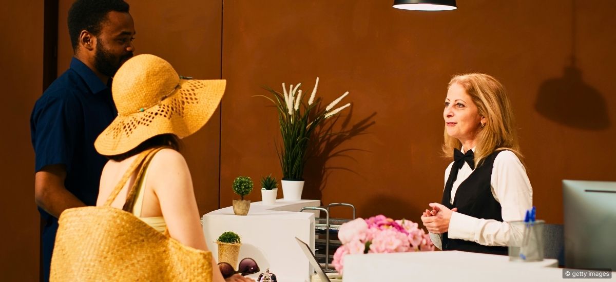 A restaurant host making eye contact with approaching guests at a warmly lit entrance