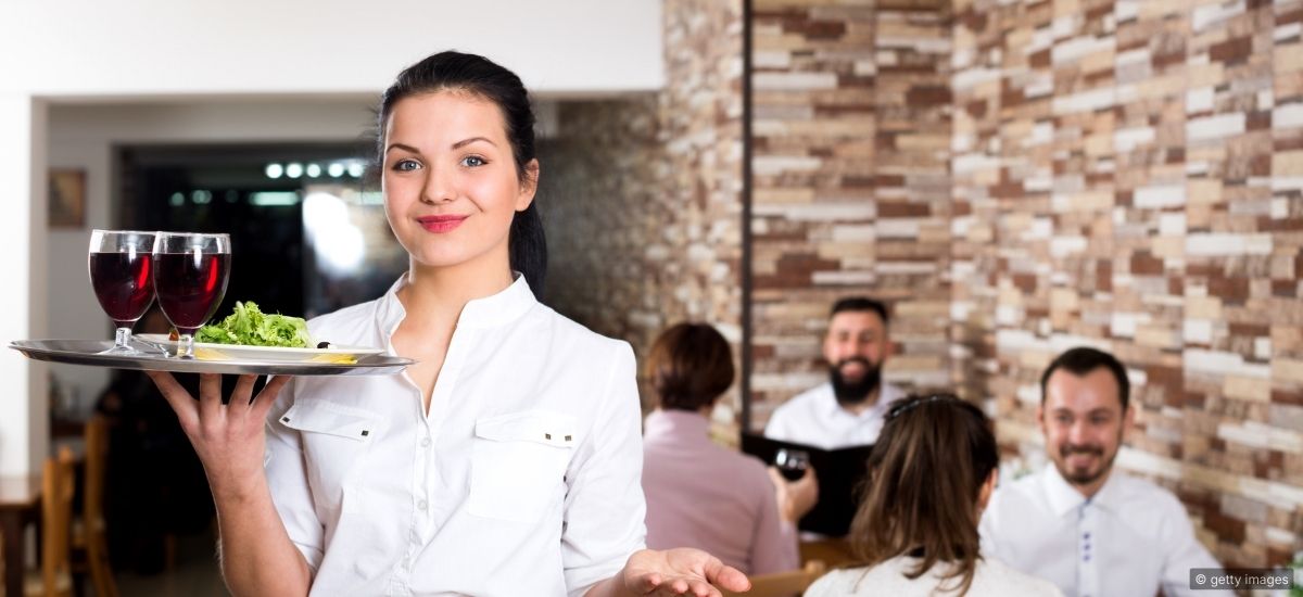 Two hospitality professionals in a pre-shift meeting practicing communication techniques in a quiet dining room